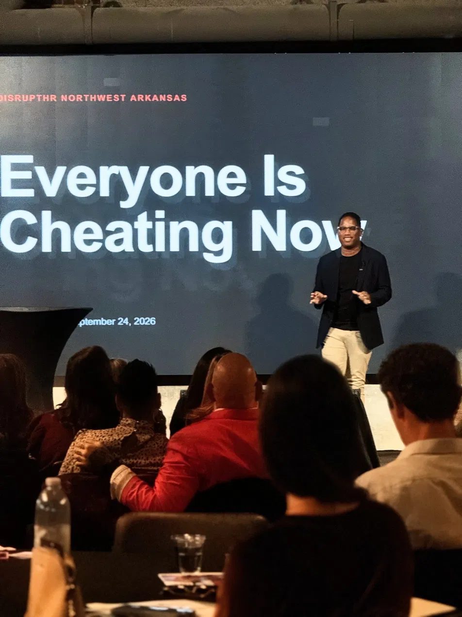 Sterling Smith on stage at DisruptHR Northwest Arkansas in front of a screen reading "Everyone Is Cheating Now"